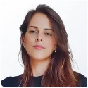 Imagem mostra o rosto de uma mulher jovem, com pele branca, olhos e cabelos longos castanhos.
