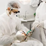 . Imagem mostra um Imagem mostra um dentista homem durante a sua prática clínica em um paciente na clínica de uma Faculdade de Odontologia em Juiz de fora